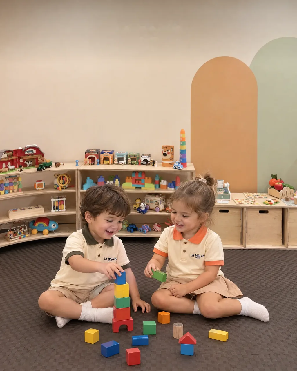 Two toddlers in La Maluk Village uniforms stacking blocks